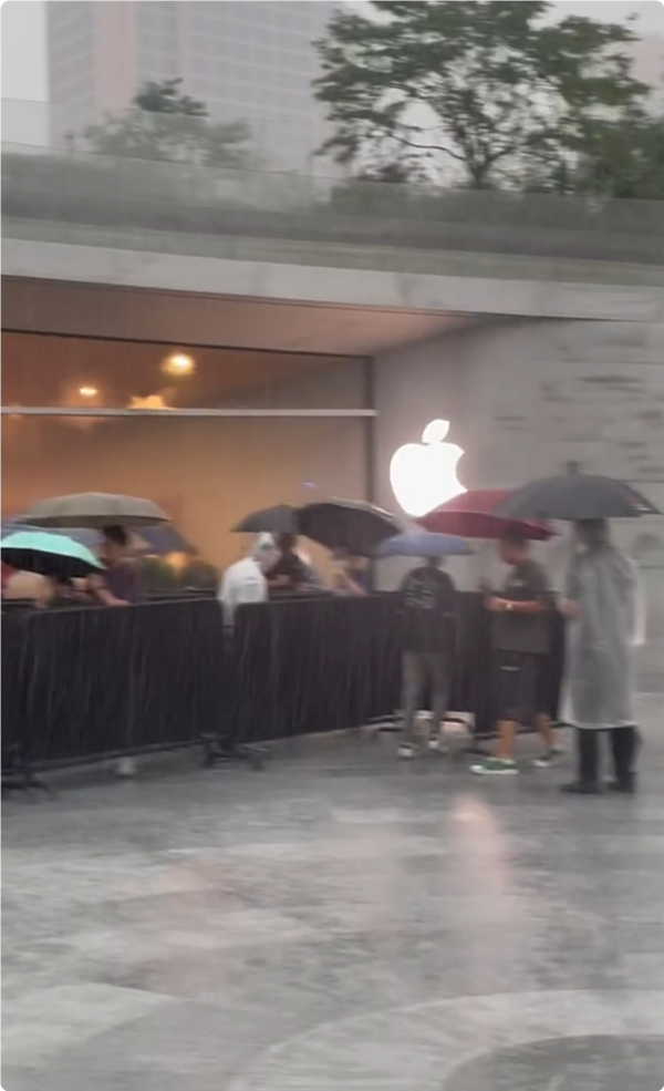 首批iPhone16用户收到新机：果粉暴雨中在AppleStore排长队取货